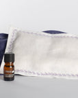 Small bottle of essential oil with two linen pillows, filled with lavender flowers and cotton.